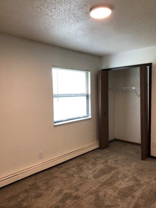 an empty room with a window and a closet