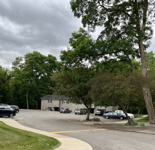 a parking lot with trees and cars in front of a house