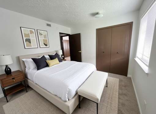 A bedroom with a large bed and a nightstand with a lamp.
