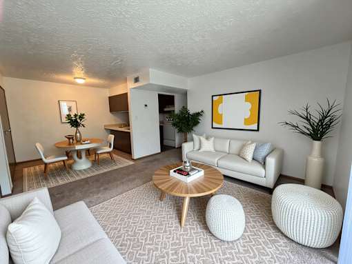 A living room with a white couch, a wooden coffee table, and a painting on the wall.