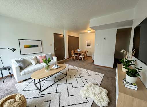 A living room with a white couch, a coffee table, and a rug.