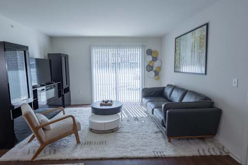 A living room with a black couch, a chair, and a television.