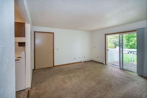 an empty living room with a sliding glass door to a patio