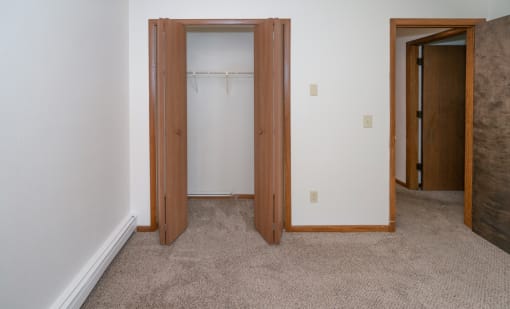 an empty bedroom with a closet and a door to a bathroom