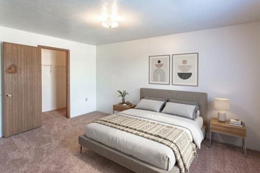 A bedroom with a bed, nightstand, and two framed pictures on the wall.