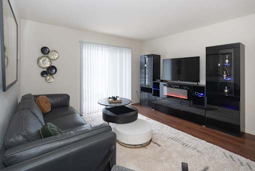 A black leather couch sits in a living room with a television and a fireplace.