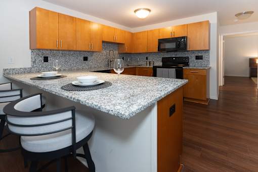 A kitchen with a granite countertop and wooden cabinets.