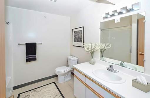 A bathroom with a toilet, sink, mirror, and a towel rack.