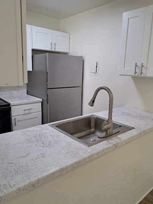 A kitchen with a sink and a refrigerator.