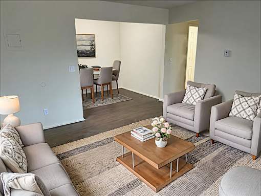 A living room with a grey couch, a wooden coffee table, and a dining table with chairs.