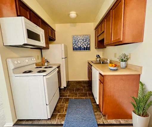 A kitchen with white appliances and brown cabinets.
