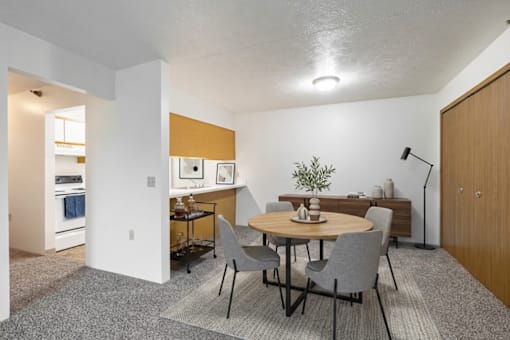 A dining room with a round table and grey chairs.