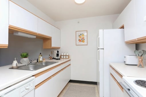 A kitchen with white cabinets and a white fridge.