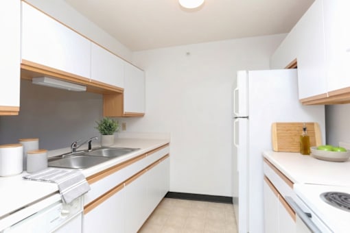 A kitchen with white cabinets and a white fridge.