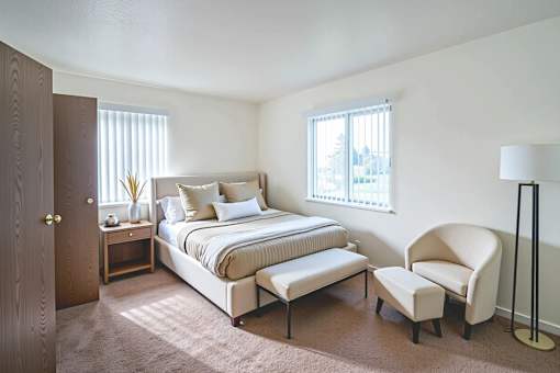 A bedroom with a bed, chair, and lamp.