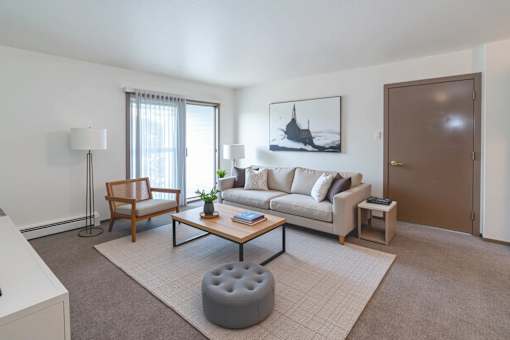 A living room with a couch, chair, ottoman, and a painting on the wall.