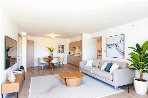 A living room with a white couch, a coffee table, and a dining table with chairs.