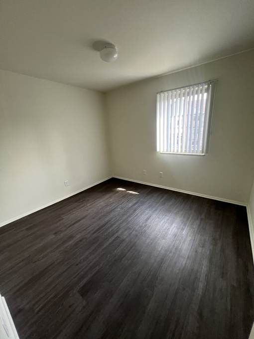 A room with a window and wooden flooring.