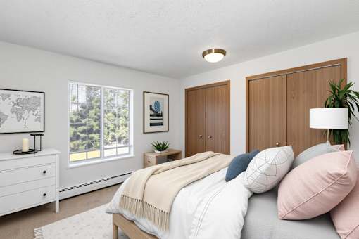 A bedroom with a bed, nightstand, and a plant.