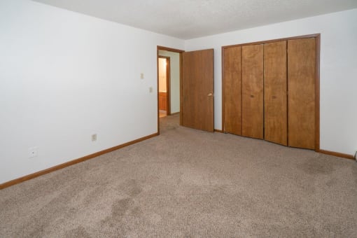 an empty living room with a carpeted floor and two closet doors