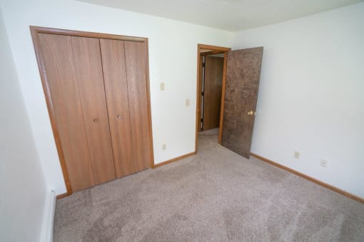 an empty room with two doors and a carpeted floor