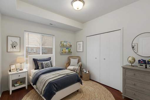 A bedroom with a bed, nightstand, and a chair.