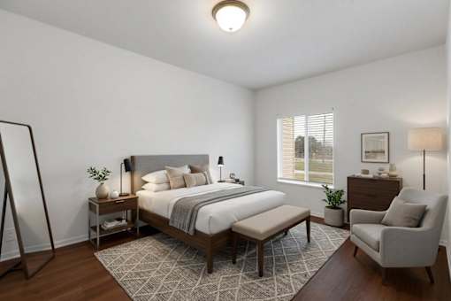 A bedroom with a large bed, a chair, and a small table.