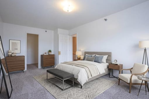 A bedroom with a large bed, a chair, and a nightstand.