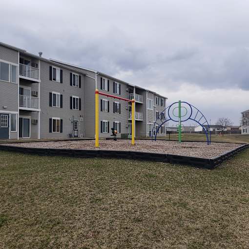 A playground with a swing set in front of apartment buildings.