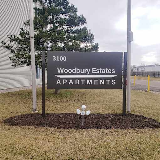 A sign for Woodbury Estates Apartments is displayed in front of a building.
