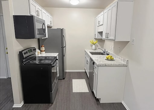 A kitchen with black appliances and white cabinets.