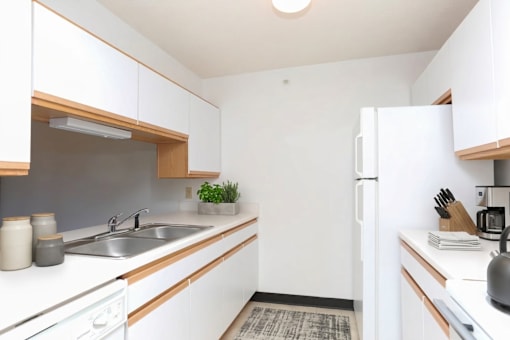 A small kitchen with white cabinets and a white fridge.