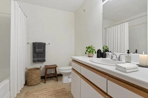 A bathroom with a white sink, toilet, and a white curtain.
