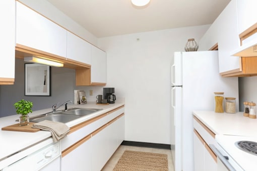 A kitchen with white cabinets and a white fridge.