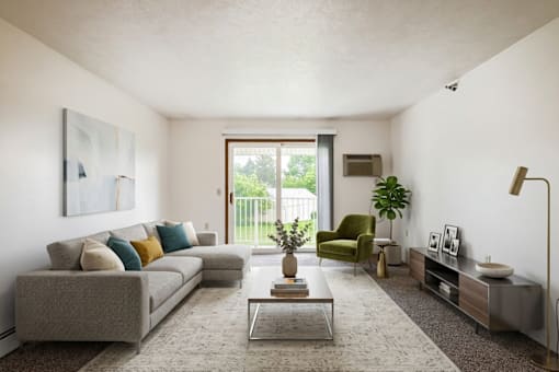 A living room with a grey couch, a green armchair, a coffee table, and a large window.