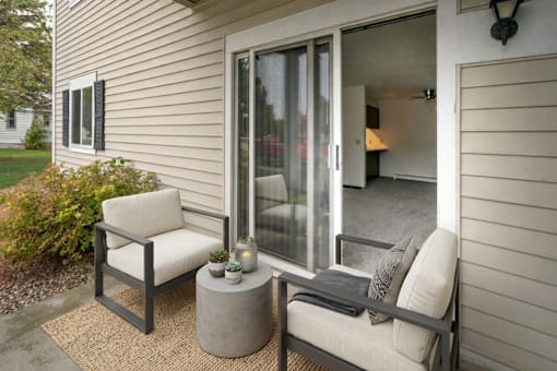 A patio with a chair and a table with candles on it.