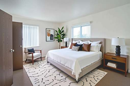 A bedroom with a large bed and a wooden nightstand.