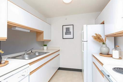 A kitchen with white cabinets and a fridge.