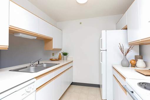 A kitchen with white cabinets and a white refrigerator.