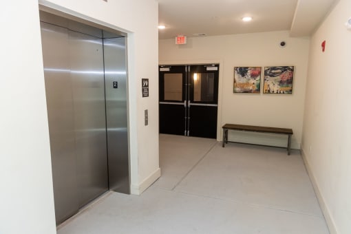 a hallway with a stainless steel elevator and a bench