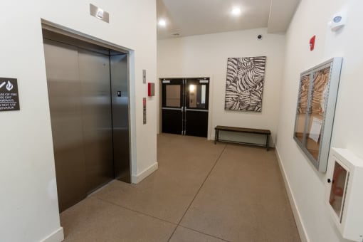a hallway with a door to a elevator and paintings on the wall