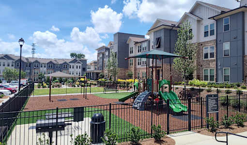 A playground with a green slide and a black fence.