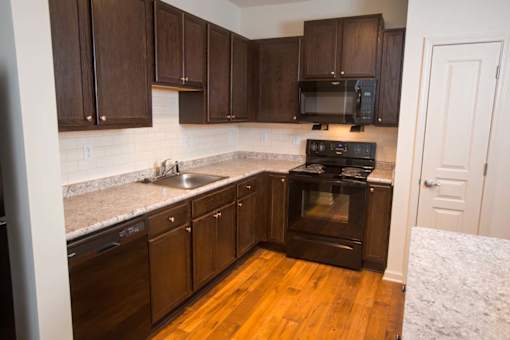 A kitchen with dark wood cabinets and a black stove top oven.