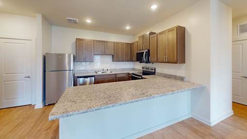 A kitchen with a granite countertop and wooden cabinets.