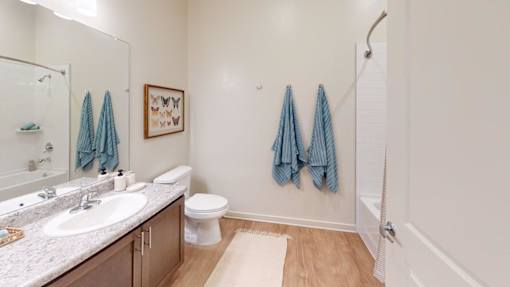 A bathroom with a white toilet, sink, and blue towels.