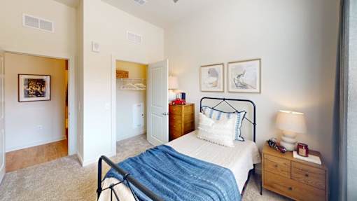 A bedroom with a bed, nightstand, and two pictures on the wall.
