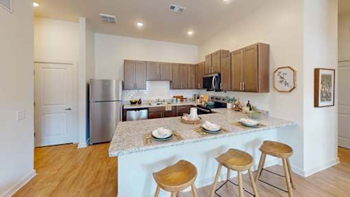 A kitchen with a marble countertop and wooden bar stools.