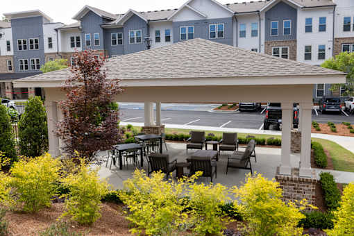 A gazebo with a table and chairs is surrounded by yellow flowers.