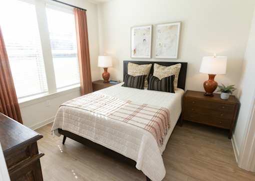 A bedroom with a bed, nightstands, and two lamps.
