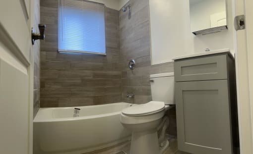 Bathroom with a toilet and a tub and a sink at Brookwood at Bay Shore in Bay Shore, NY 11706